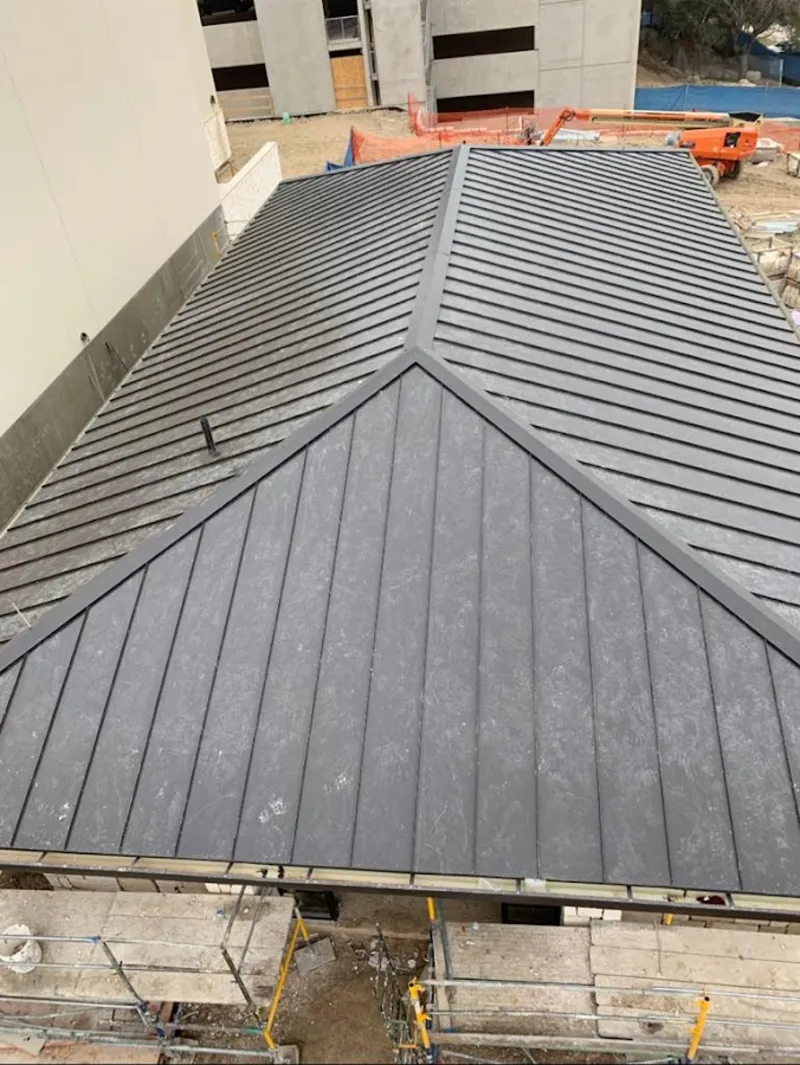 Commercial metal roof construction with crane equipment in Alpine