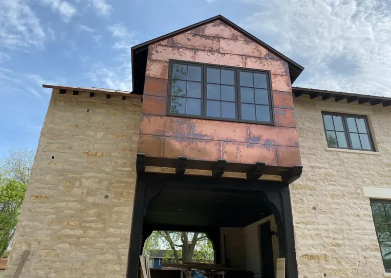 Copper metal panel facade on a stone building for Skylight Installation in Alpine